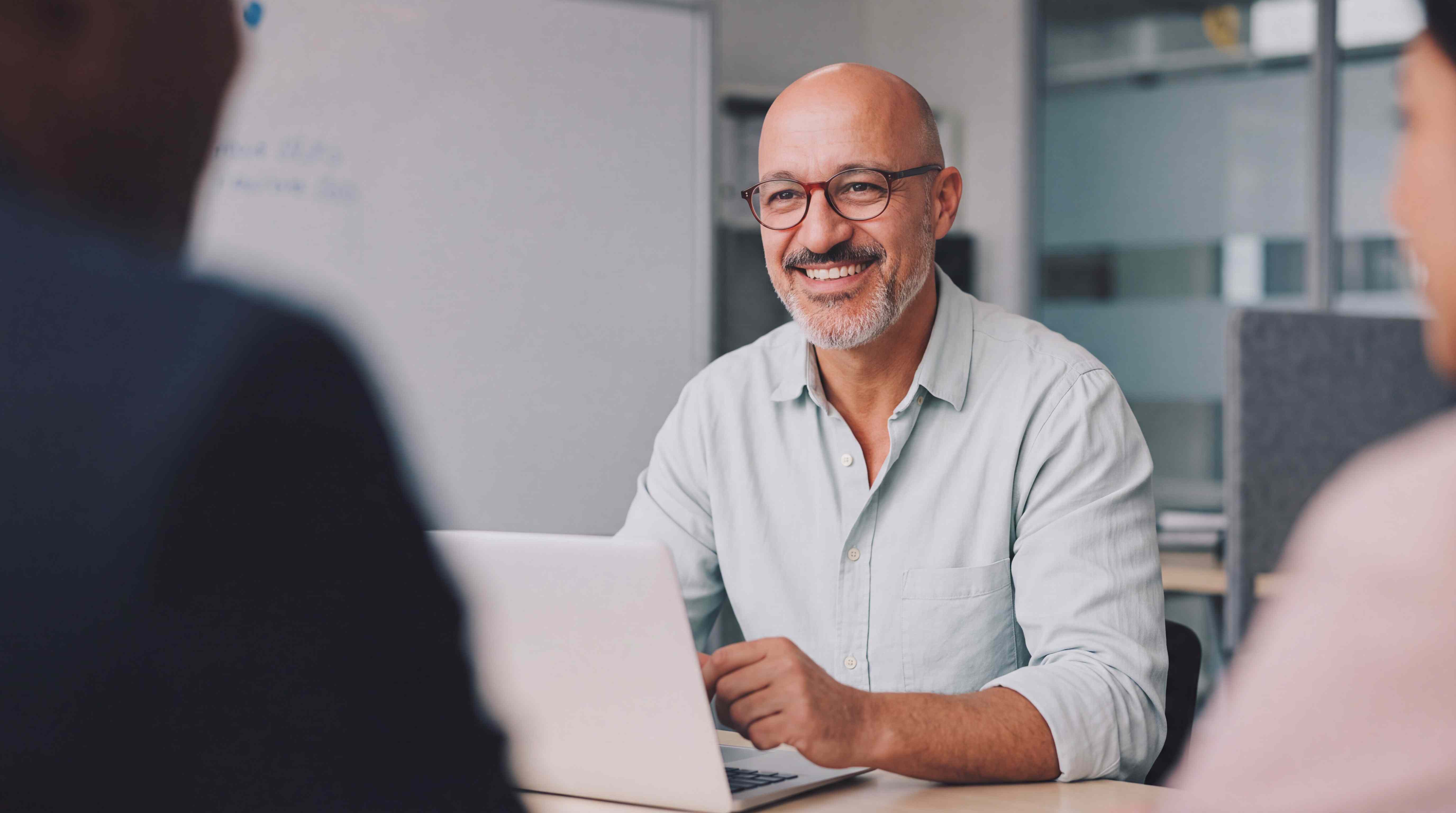 A professional smiling with colleagues during a workplace language training session
